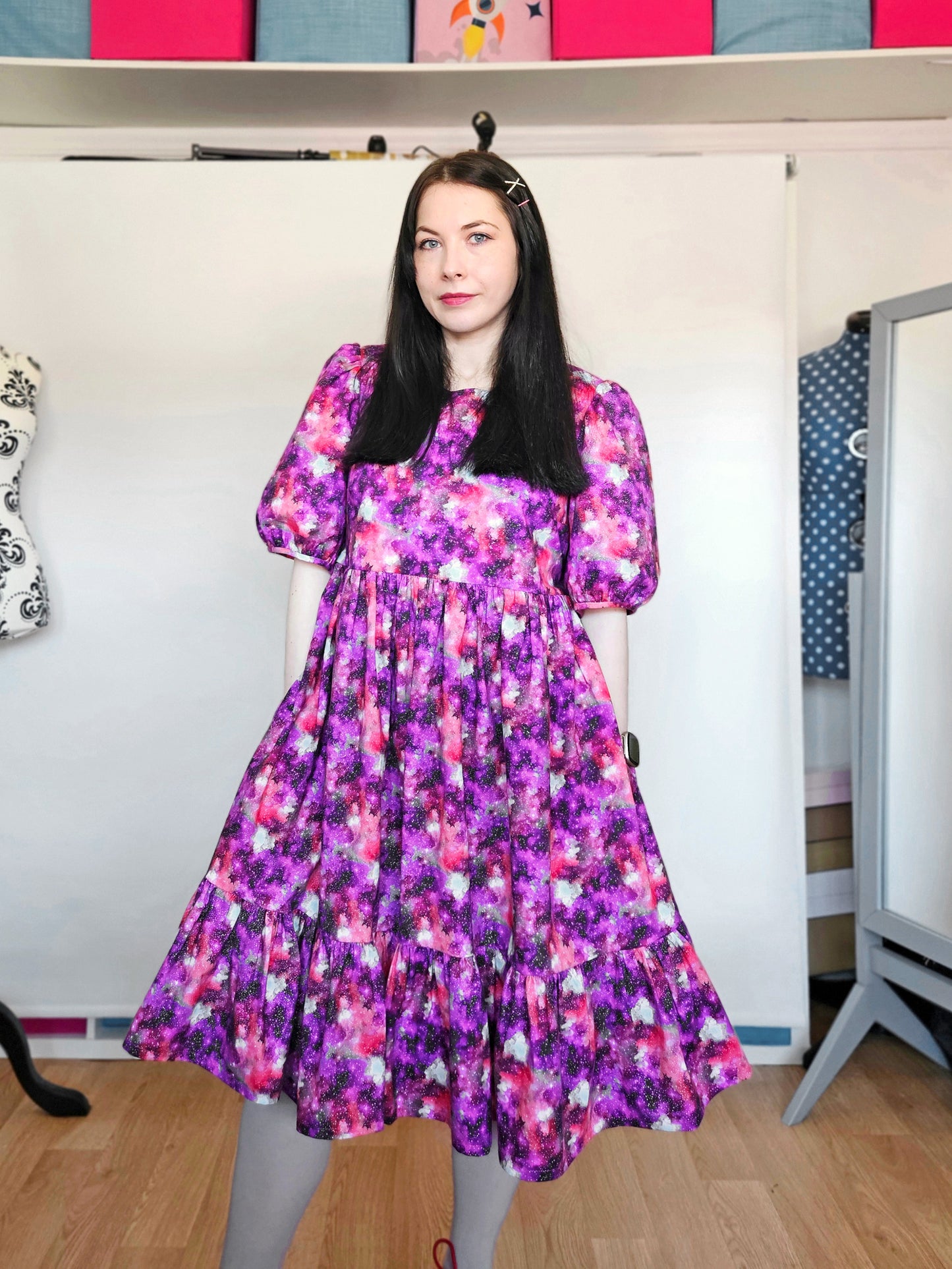 Woman wearing a purple and pink space print dress.