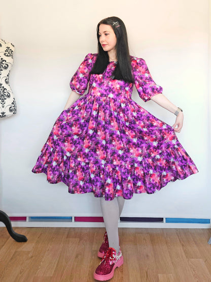 Woman wearing a purple and pink space print dress.