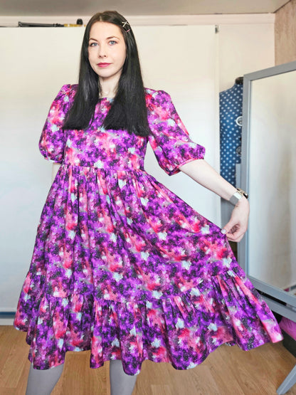 Woman wearing a purple and pink space print dress.