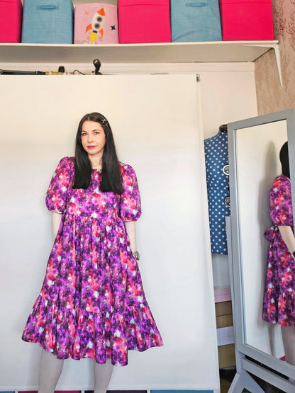 Woman wearing a purple and pink space print dress.