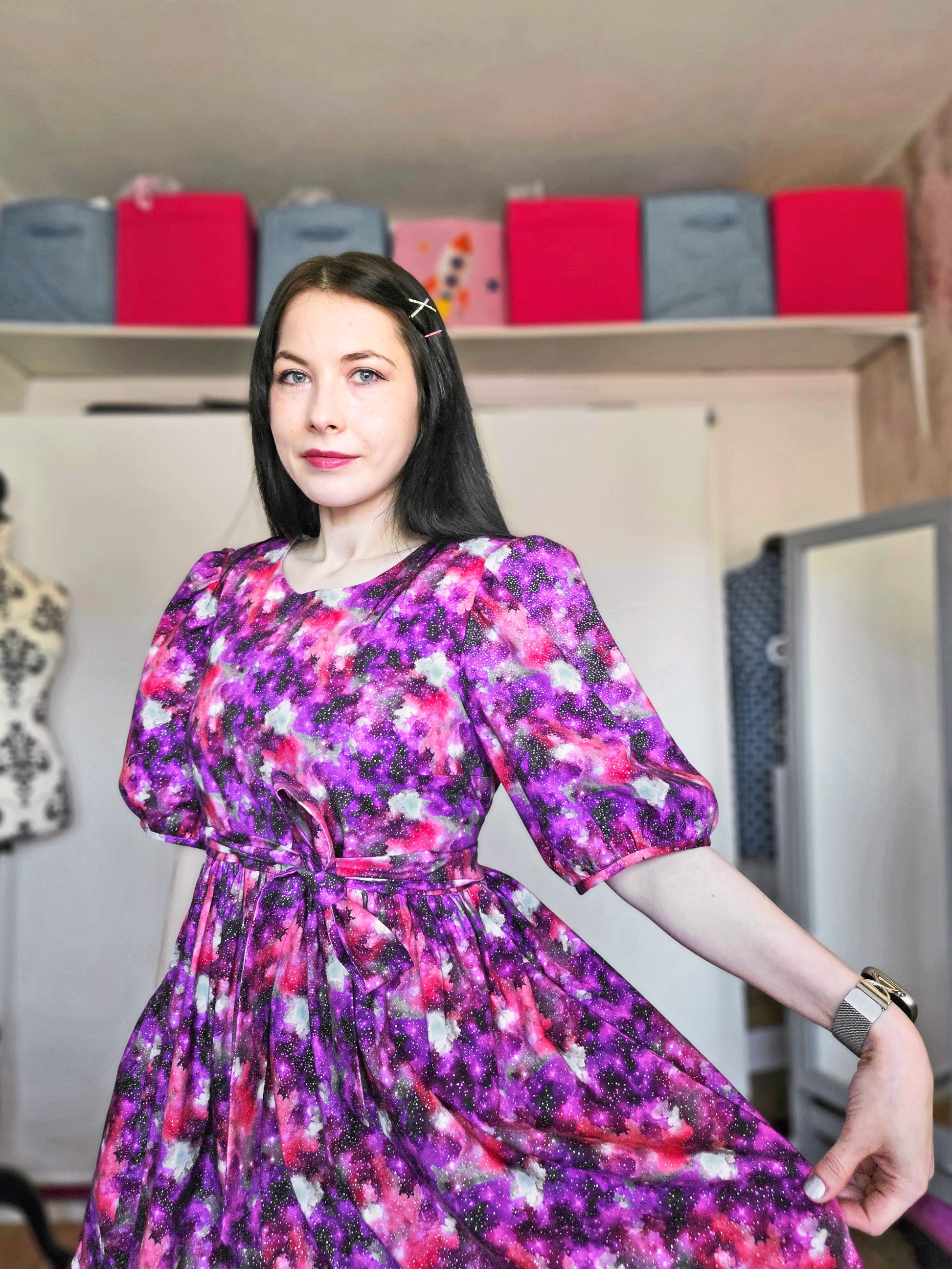 Woman wearing a purple and pink space print dress.
