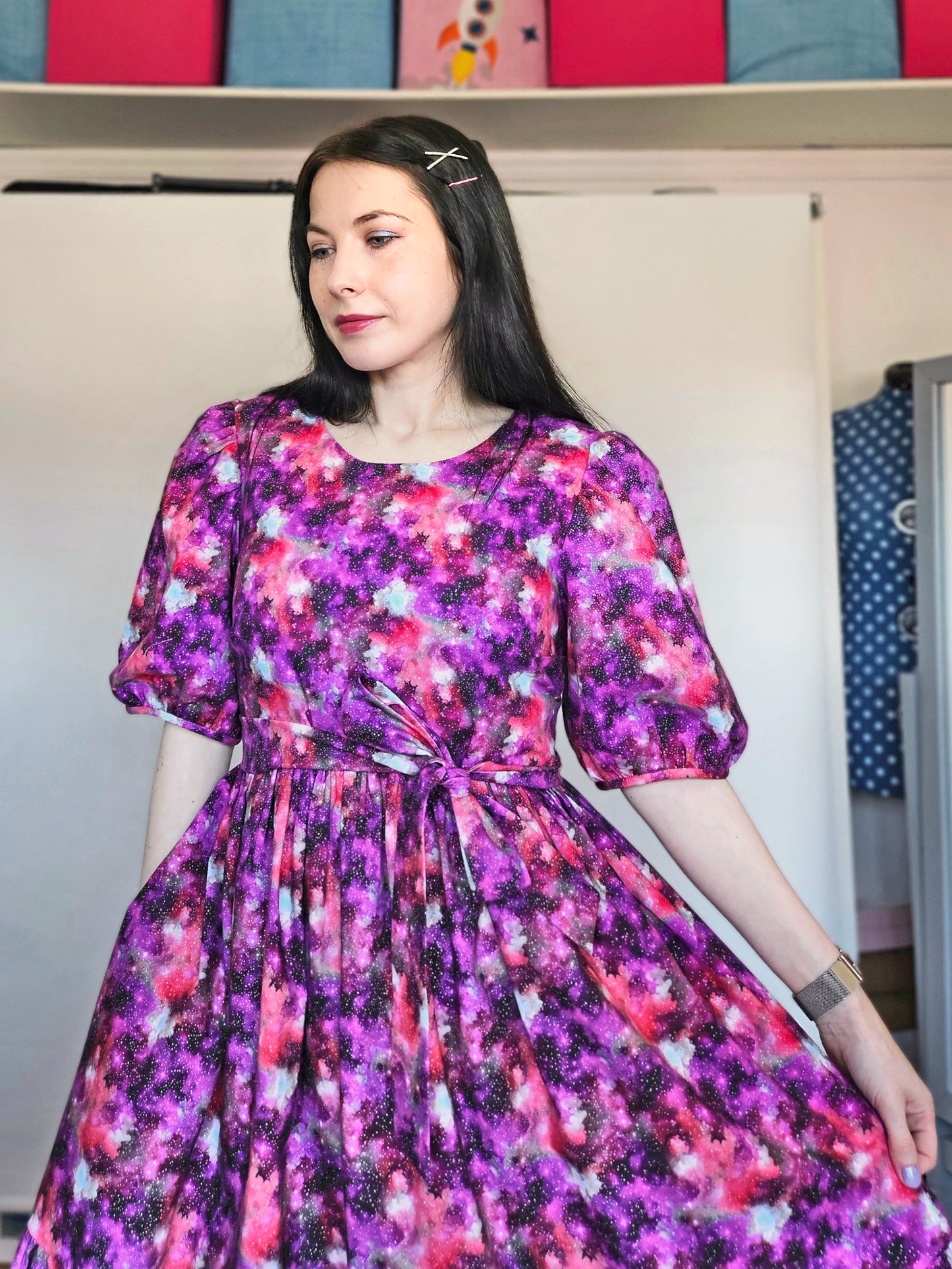 Woman wearing a purple and pink space print dress.
