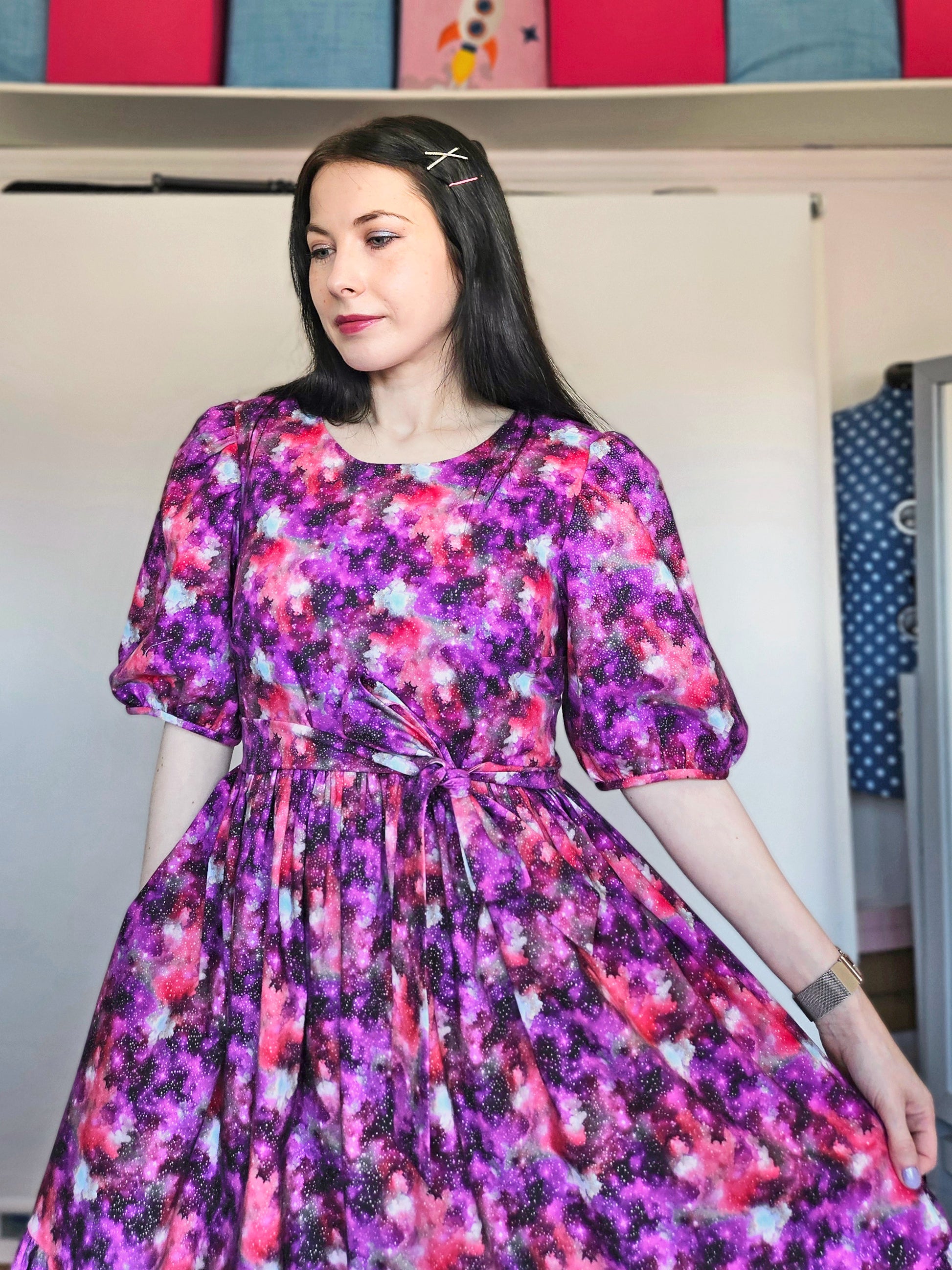 Woman wearing a purple and pink space print dress.
