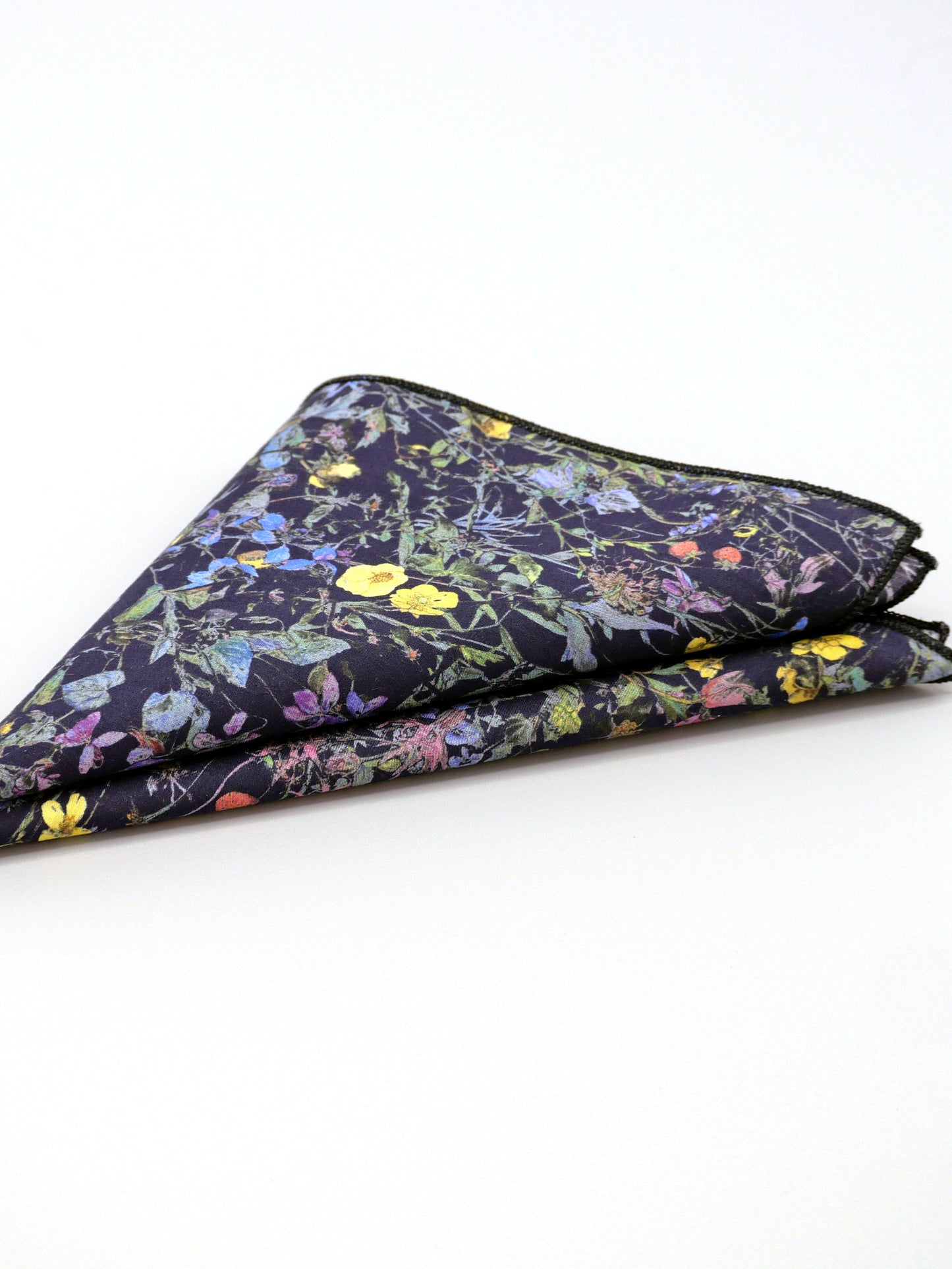 Floral patterned Liberty print pocket square folded into a triange on a pale grey background