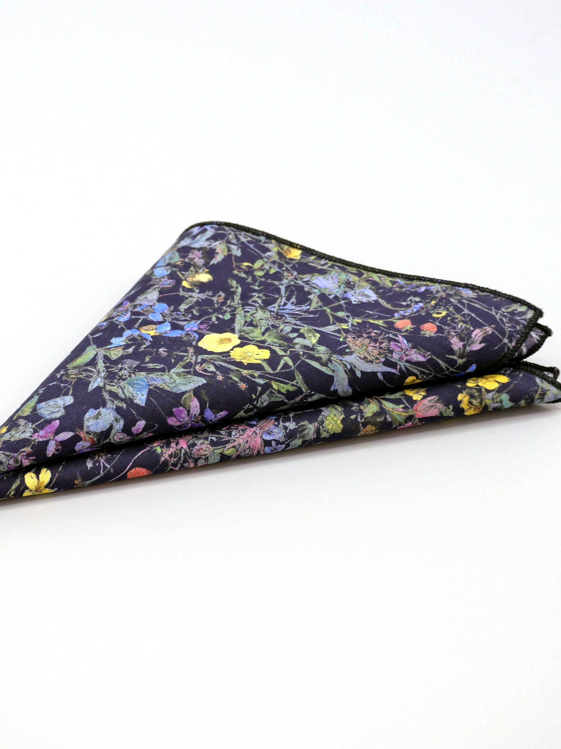 Floral patterned Liberty print pocket square folded into a triange on a pale grey background