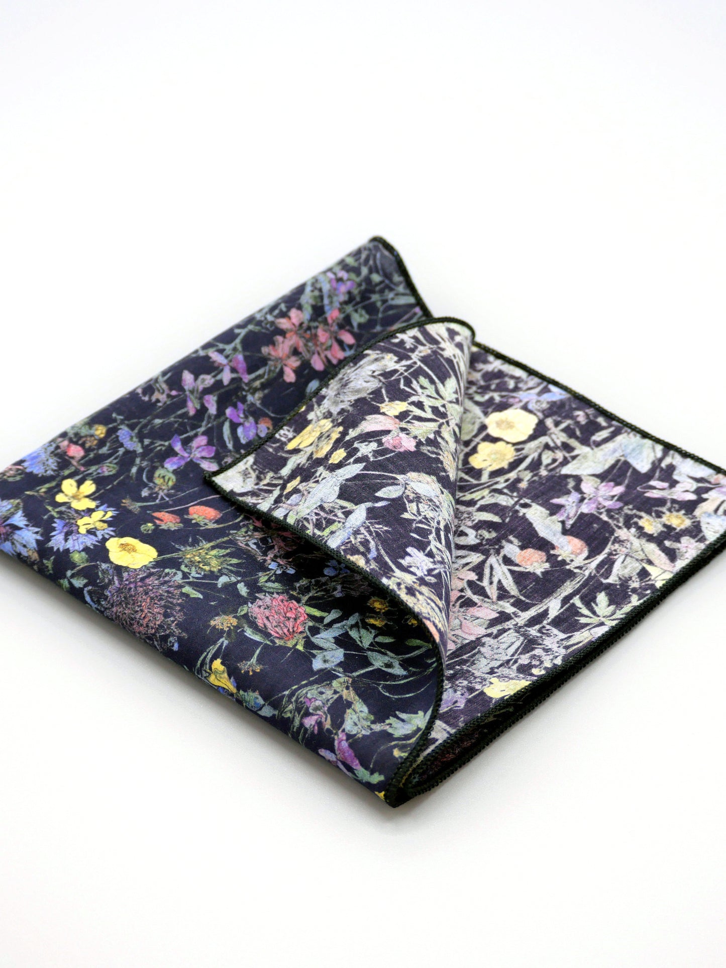 Floral patterned Liberty print pocket square with one corner folded over on a pale grey background