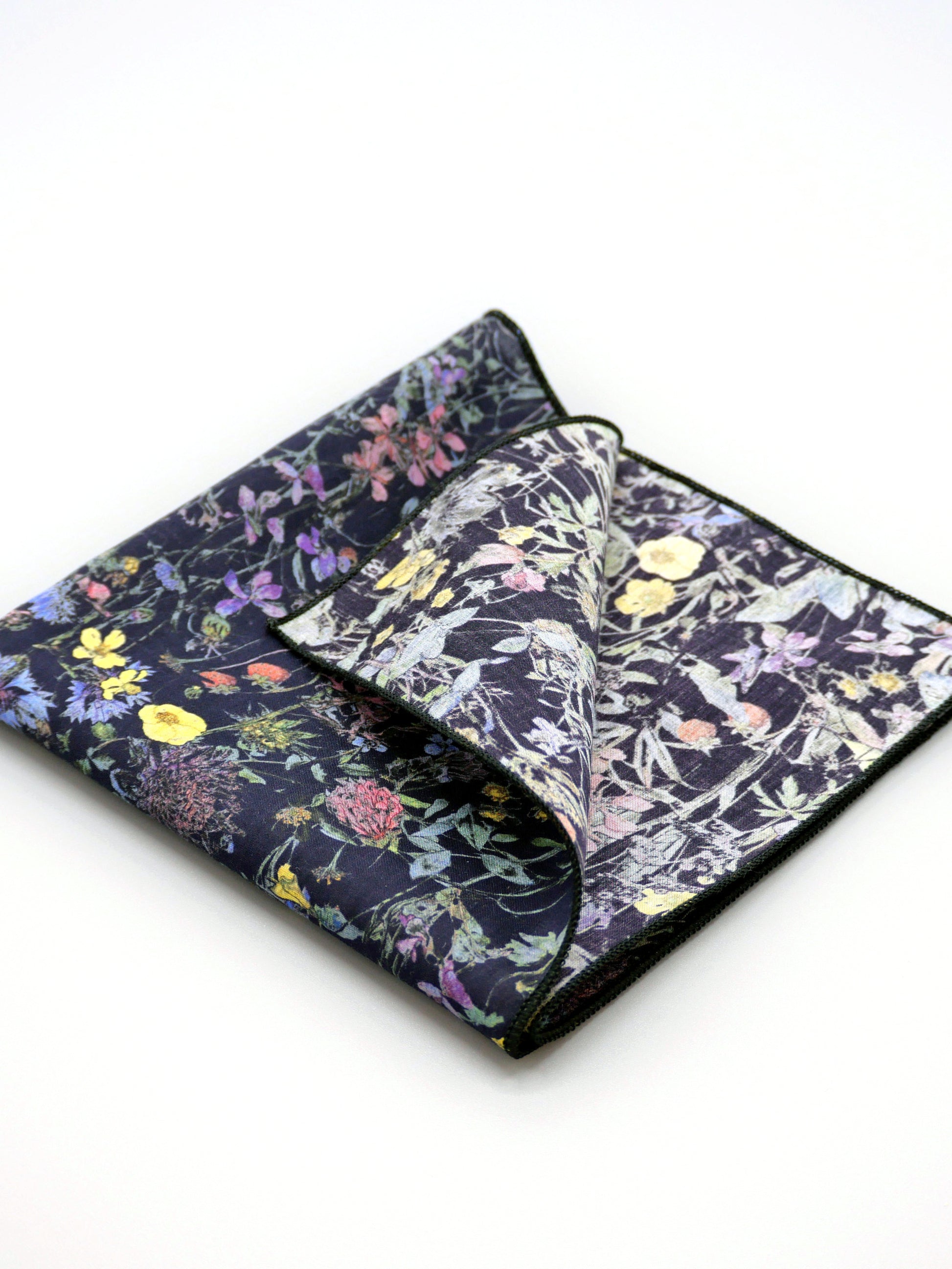 Floral patterned Liberty print pocket square with one corner folded over on a pale grey background