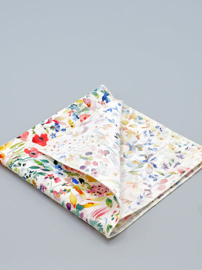 Colourful floral patterned pocket square with cone corner folded over on a grey background