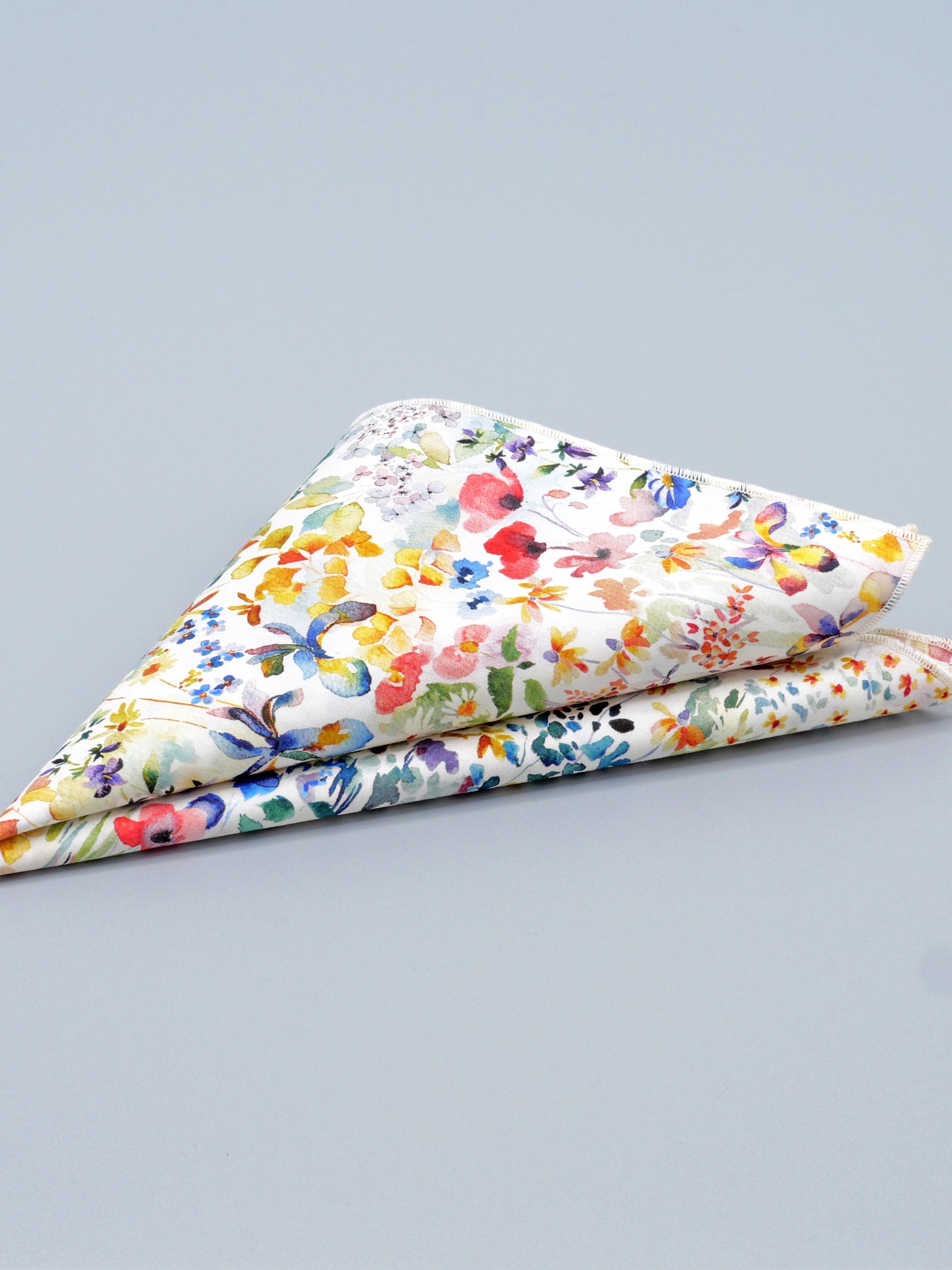Colourful floral patterned pocket square folded in triangular shape on a grey background
