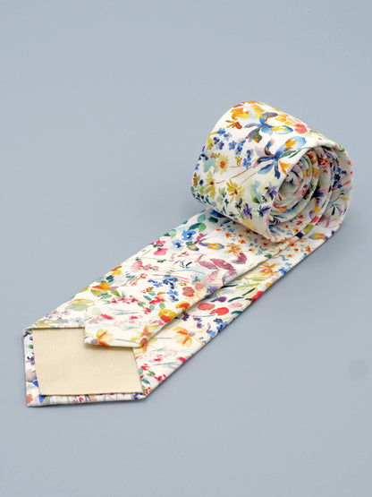 Floral watercolour style patterned tie rolled up on a grey background, with a cream lining