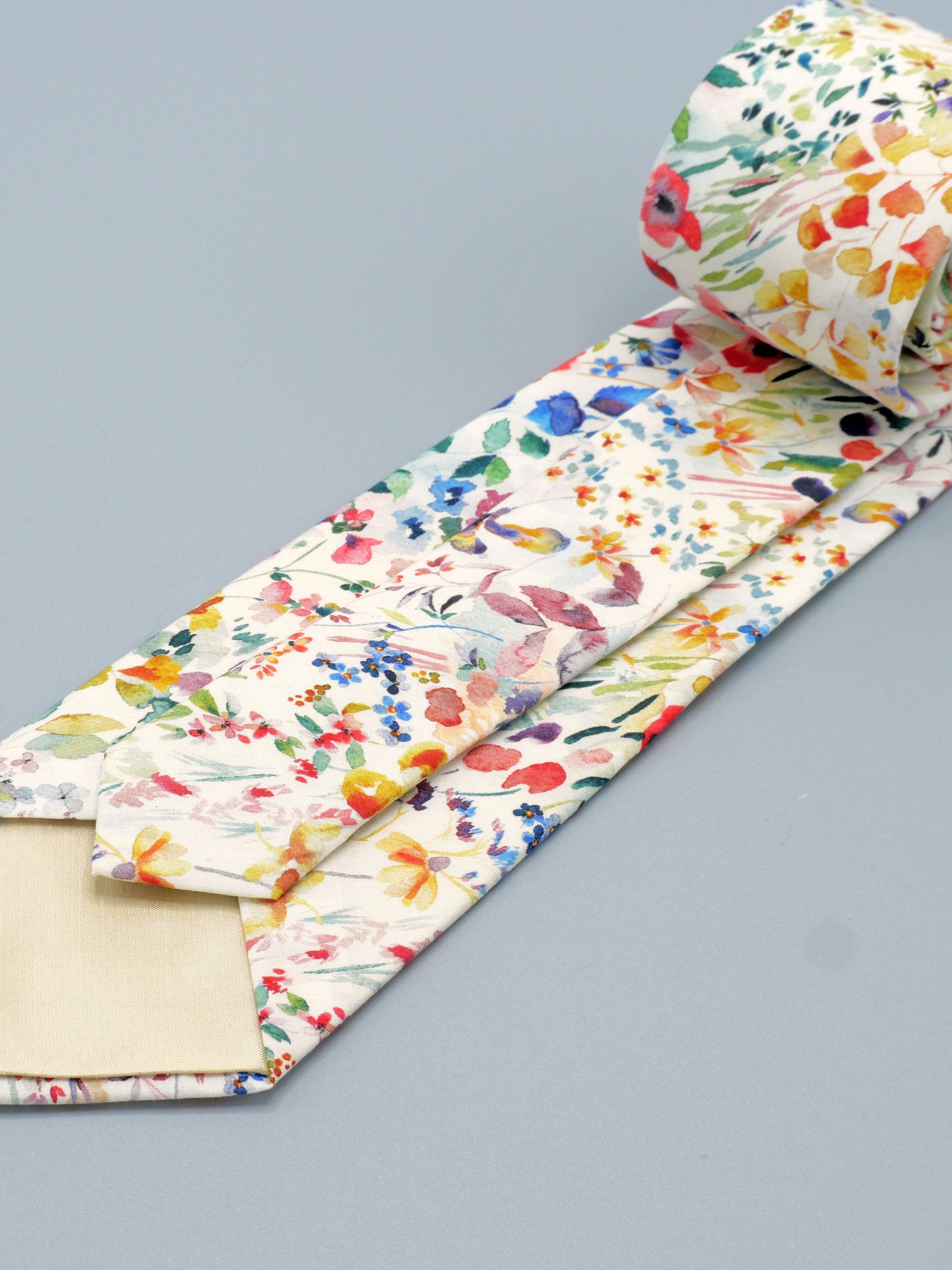 Floral watercolour style patterned tie with a cream-coloured tip lining on a grey background