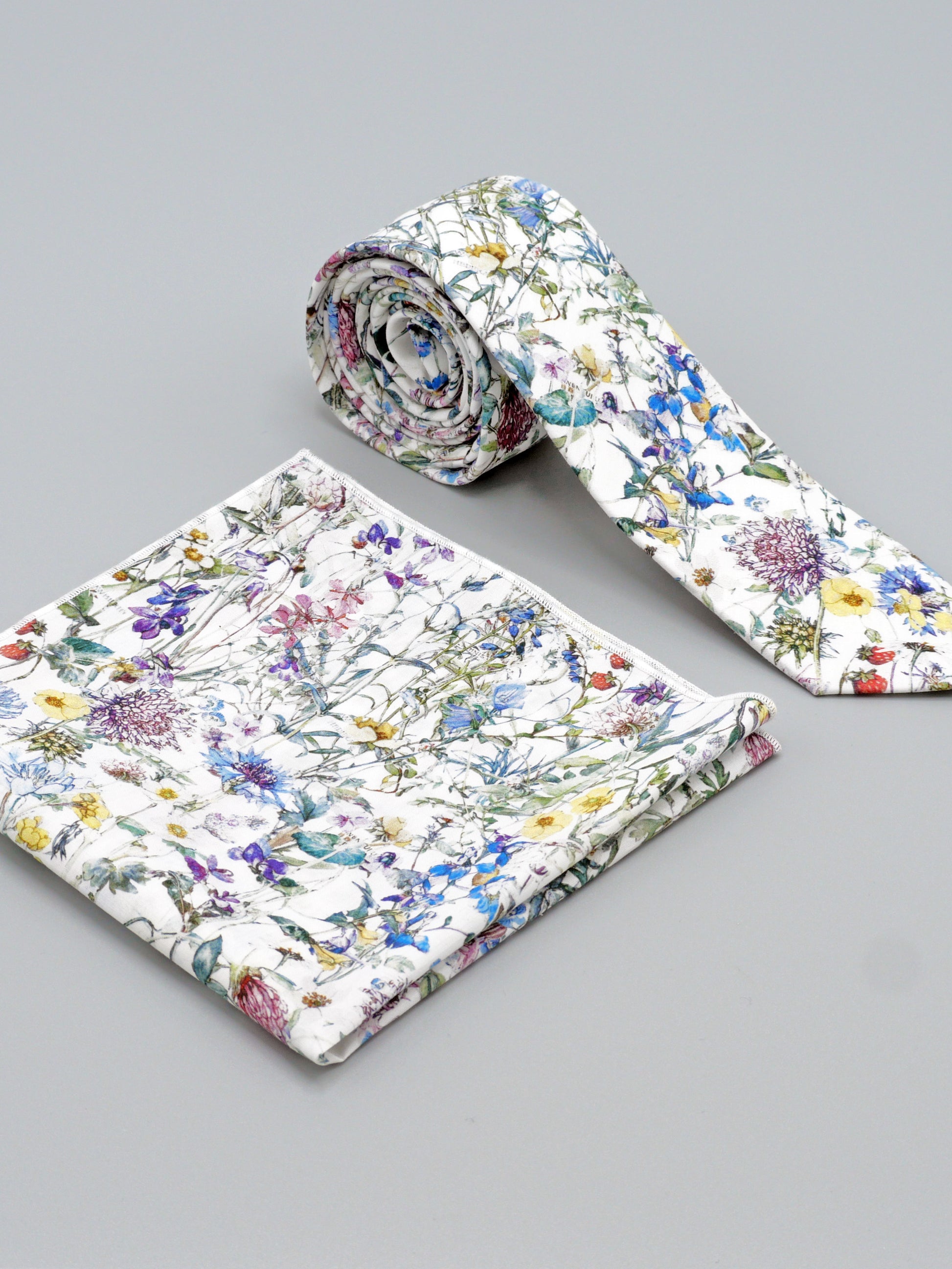 Floral-patterned tie and a matching pocket square on a grey background