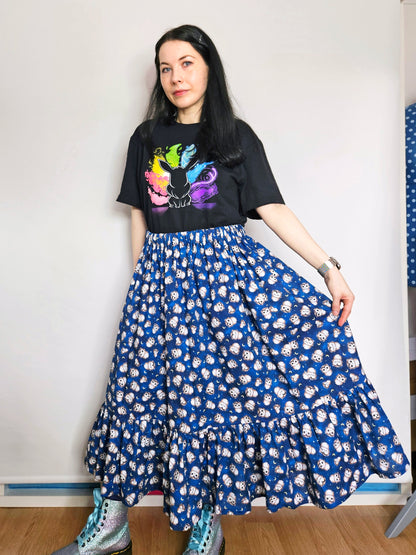 Person wearing a black t-shirt with colourful design and a blue owl print skirt