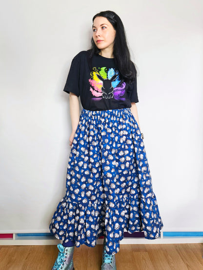 Person wearing a black t-shirt with colourful design and a blue owl print skirt