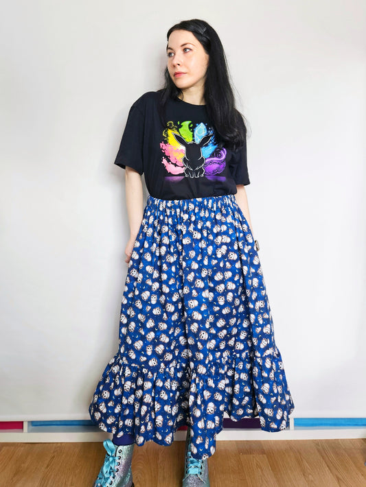 Person wearing a black t-shirt with colourful design and a blue owl print skirt