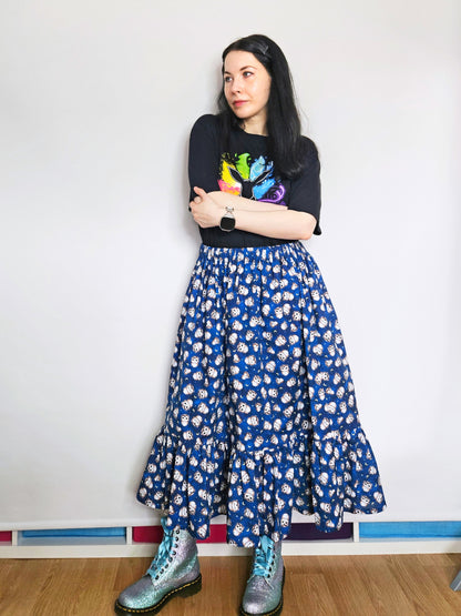 Person wearing a black t-shirt with colourful design and a blue owl print skirt