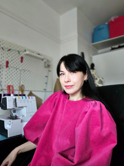 Woman wearing a pink dress in a sewing room.