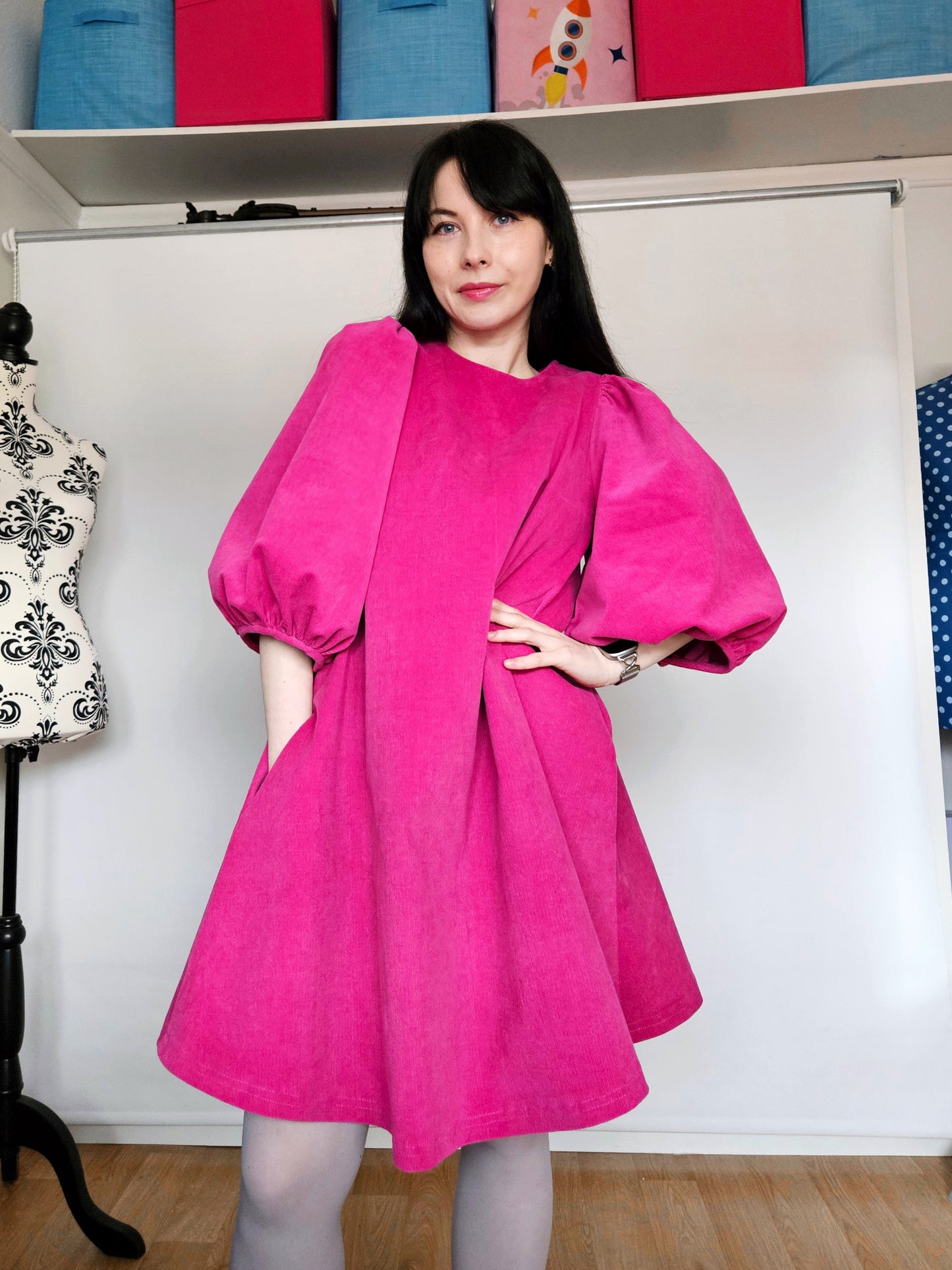 Woman wearing a bright pink dress with puffed sleeves.