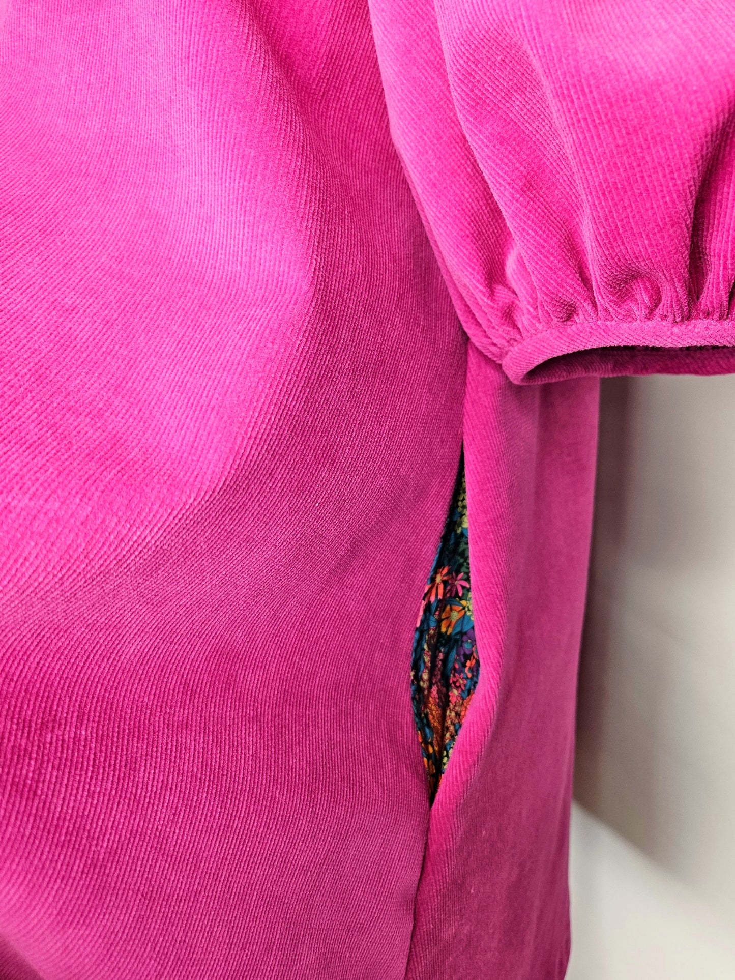 Close-up of a bright pink dress with a floral pattern pocket lining peeking out.