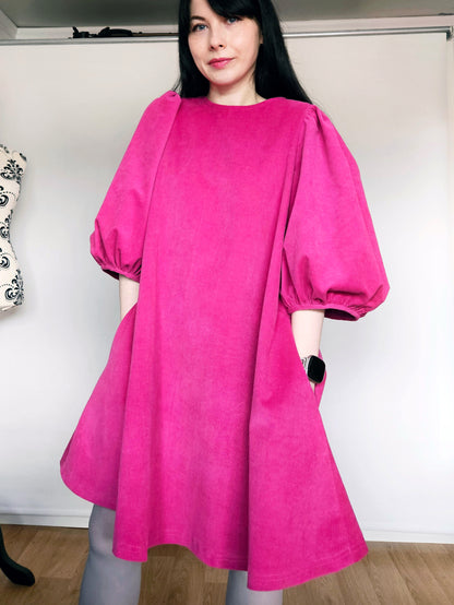 Woman wearing a bright pink dress with puff sleeves against a white background