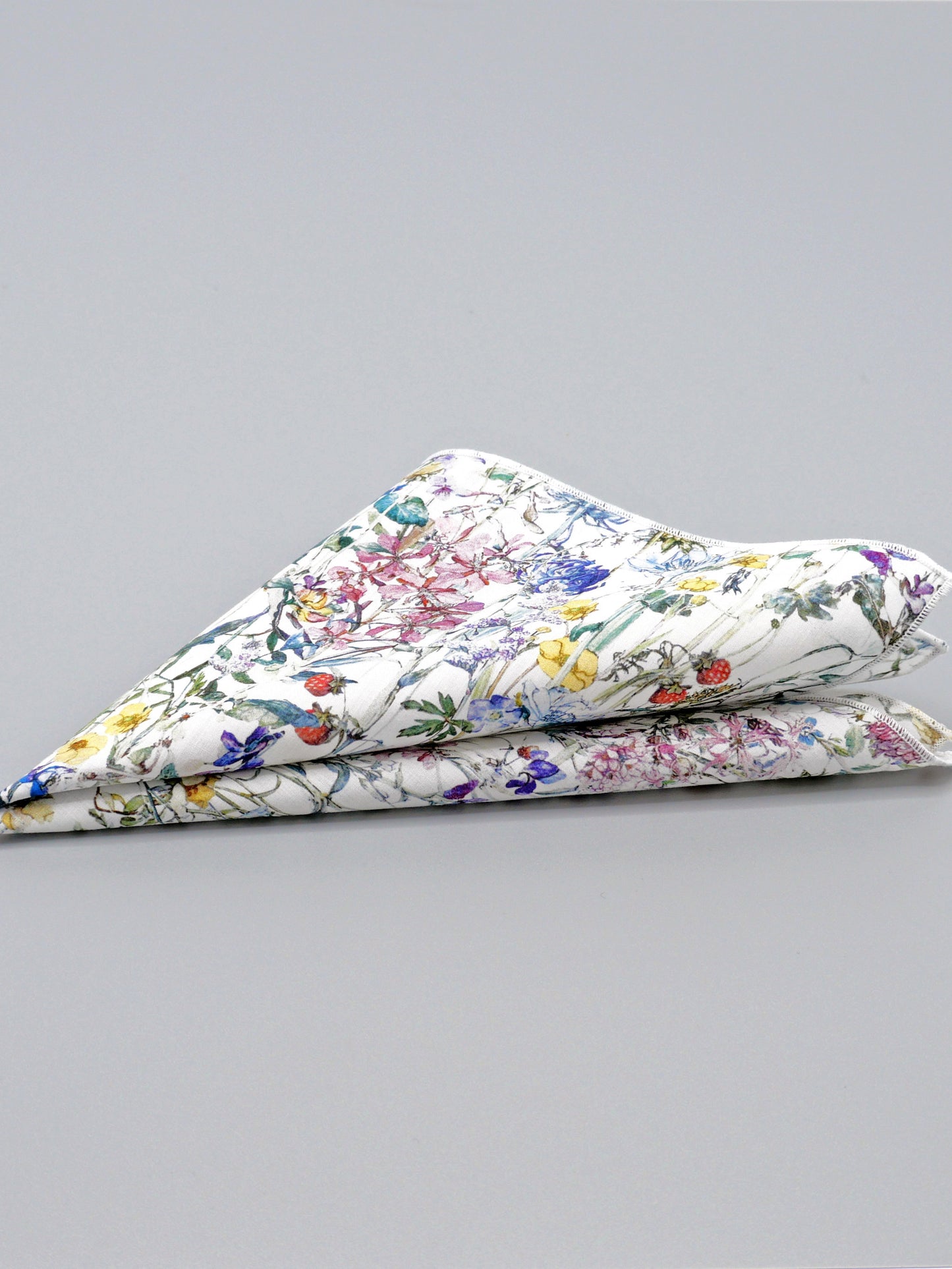 Floral patterned pocket square folded into a triangle on a grey background