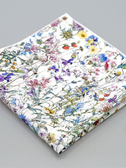 A close-up of a floral patterned pocket square on a grey background