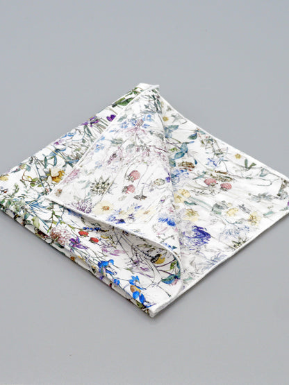 Floral patterned pocket square with a corner folded over on a grey background